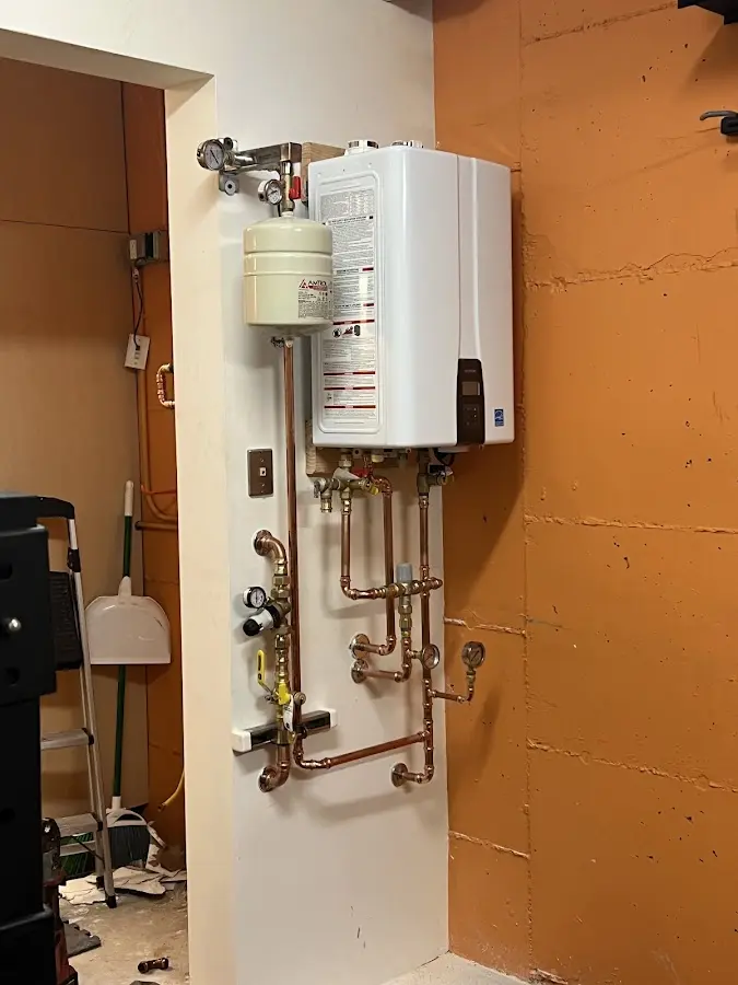 Plumbing technician inspecting water heater connections in Ewing